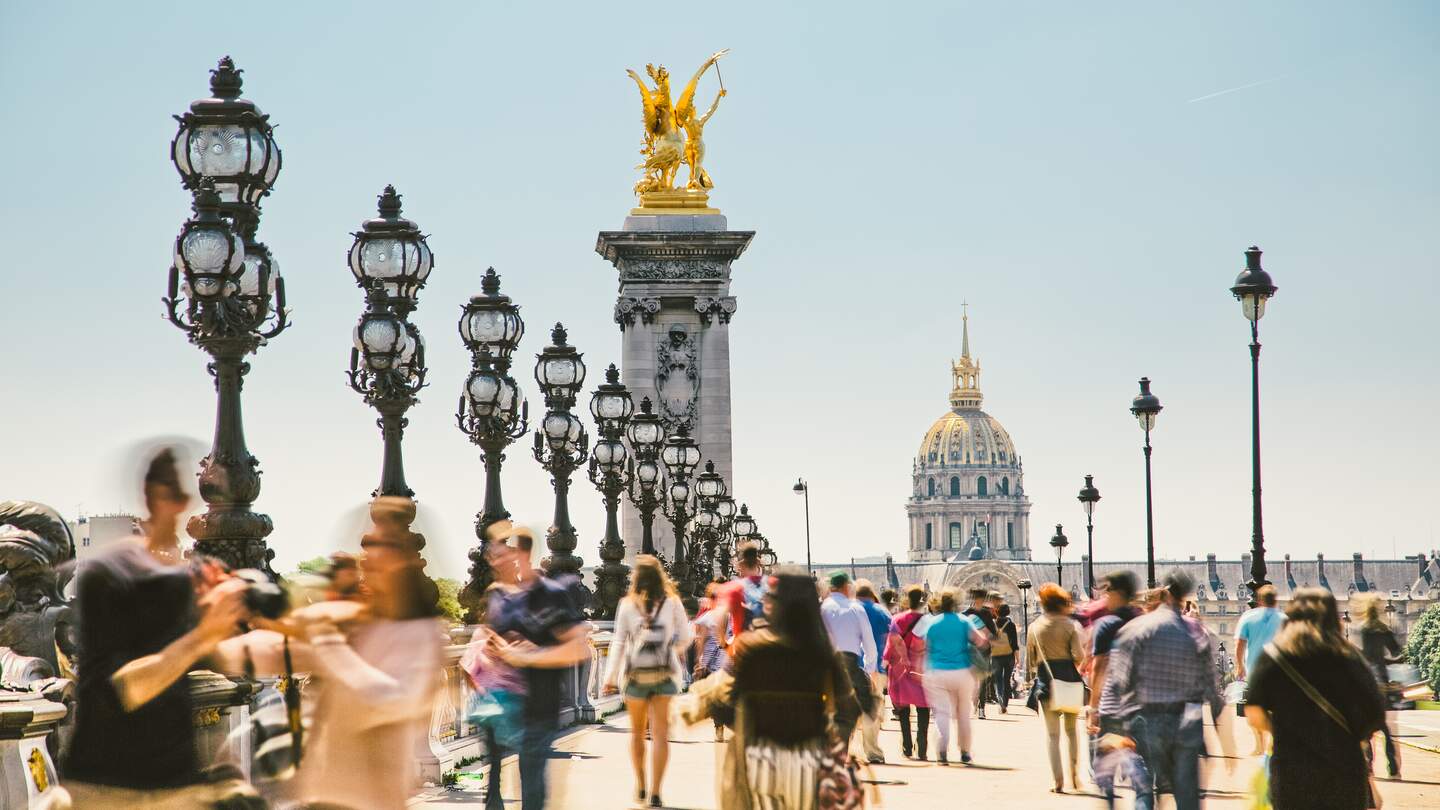 Fußgänger laufen auf der Pont Alexandre III in Paris an einem sonnigen Sommertag. | © Gettyimages.com/espiegle