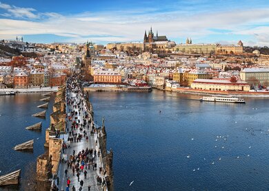 Auf der Karlsbrücke in Prag laufen Touristen im Winter. Im Hintergrund ist das Viertel Mala Strana und die Prager Burg.  | © Gettyimages.com/rusm
