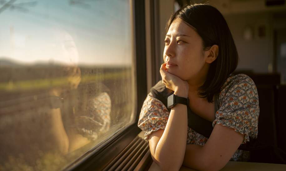 Asiatische Frau schaut nachdenklich aus dem Zugfenster | © Gettyimages.com/recep-bg