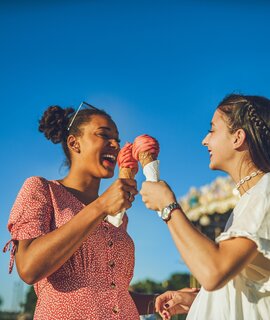 Zwei fröhliche, junge Frauen haben einen spaßigen Tag in Paris, Eis essend auf dem Rummel | © Gettyimages.com/Charday Penn