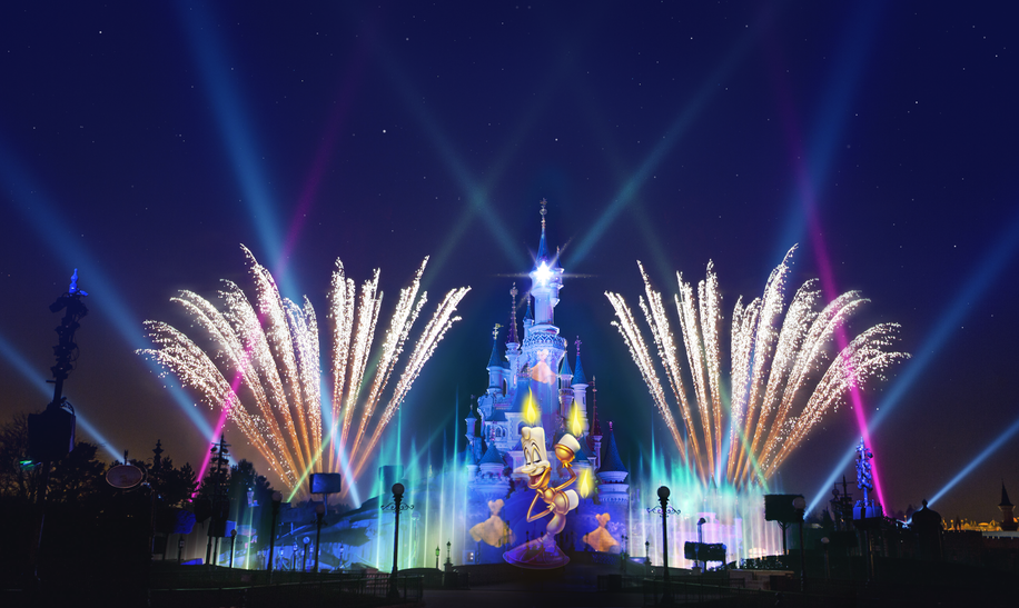 Sleeping Beauty Castle bei Nacht in Disneyland® Park mit Feuerwerk und Laser Disney Dreams®, auf dem Schloss ist Lumiere zu sehen | © Disney