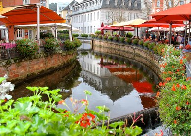 Blick auf die Saar in Saarburg mit Restaurants am Ufer und alten Häusern im Hintergrund