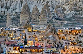 Blick auf die Felsenbauten und die beleuchteten Häuser von Göreme in Kappadokien in der Türkei | © GettyImages.com/only fabrizio