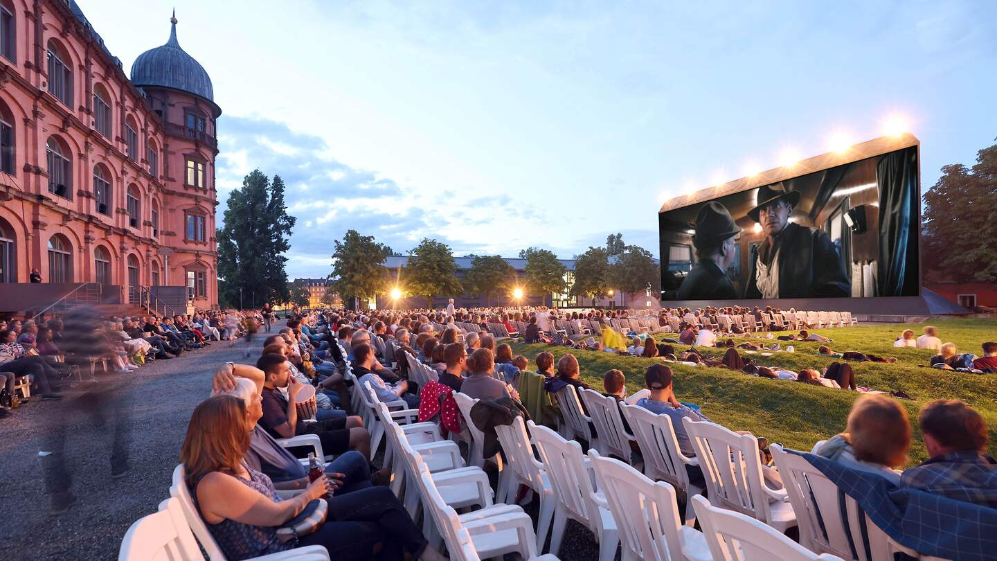 Open Air Kino am Schloss Gottesaue mit Stuhlreihen und ersten Besuchern mit Blick auf die Kinoleinwand im Bildhintertergrund rechts die Fassde von Schloss Gotteesaue in Karlsruhe | © jodo-Foto Joerg Donecker