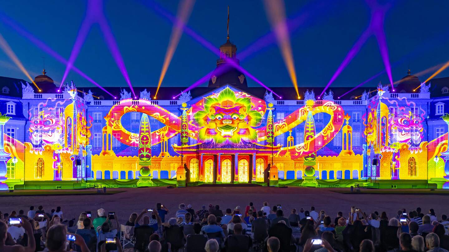 Blick auf die mudimedial gestaltete Fassade des Karlsruher Schlosses bei den Schlosslichstspilen 2023 am Abend mit dem Projekt The Fox The Folks, Bhinneka Express | © Jürgen Rösner Karlsruhe