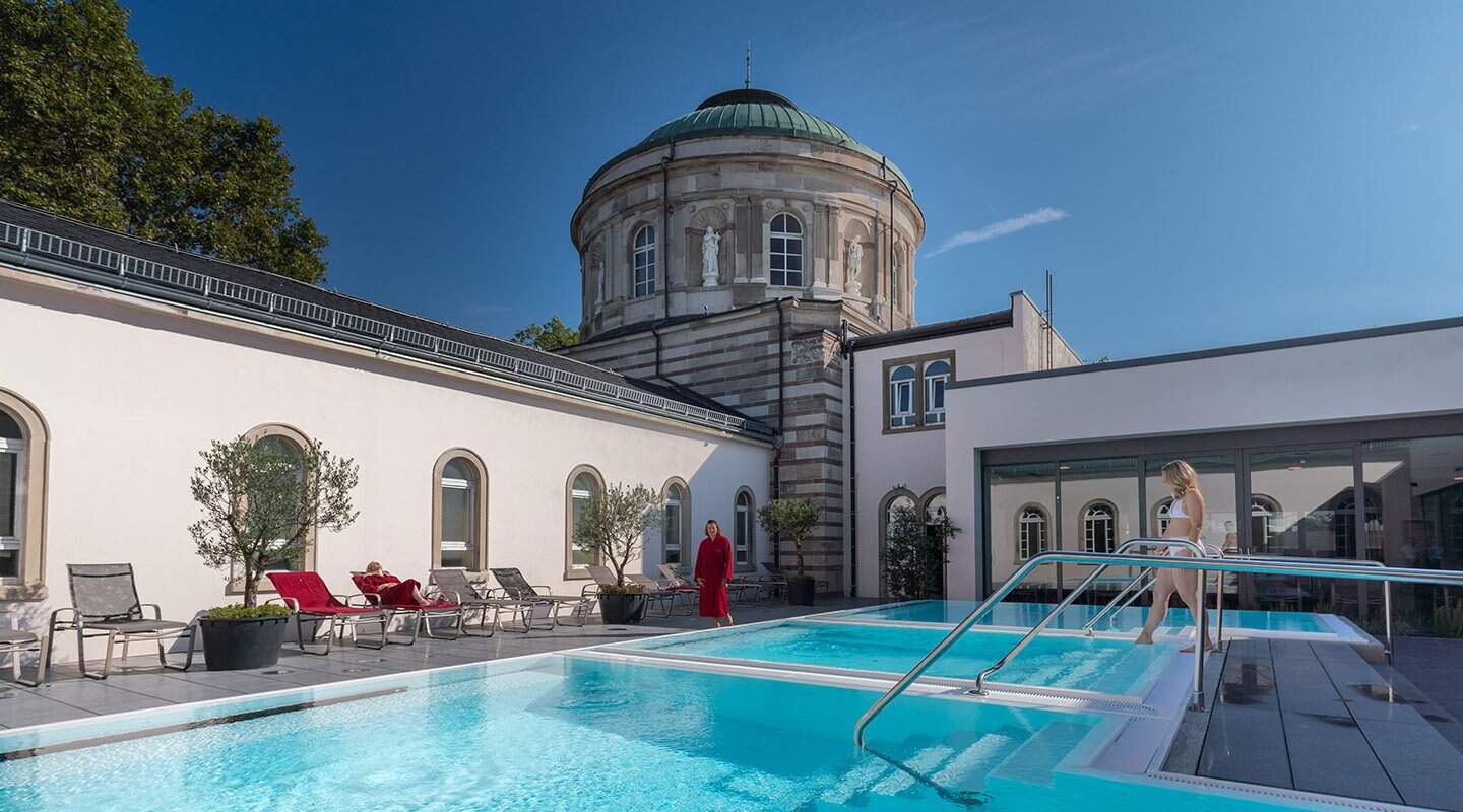Blick in den Außenbereich mit Pools und Sonneliegen sowie weiblichen Badegästen des historischen Vierordtbades in Karlsruhe  | © Stadt Karlsruhe Bäderbetriebe