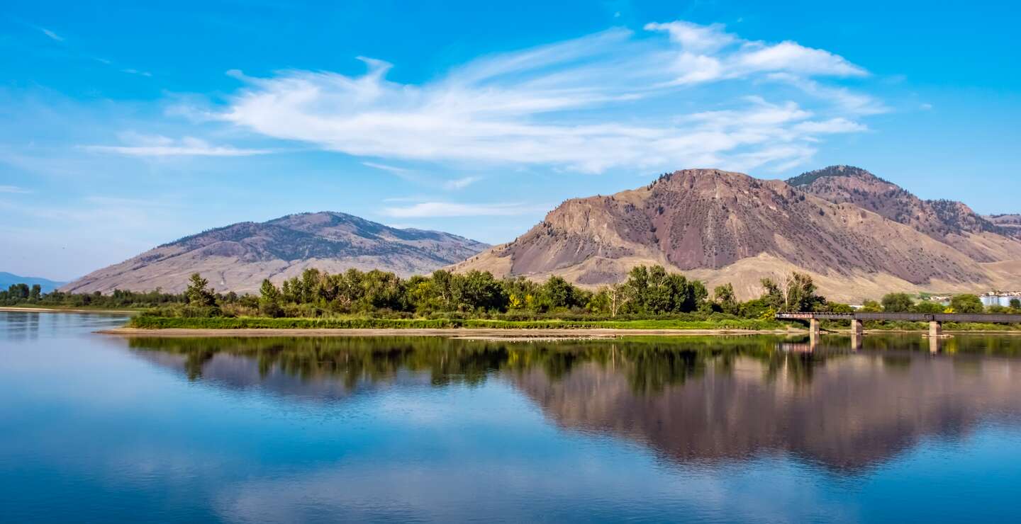 Thomson River, Kamloops, BC mit Bergkette und Eisenbahnbrücke in der Ferne. | © GettyImages.com/BriBar