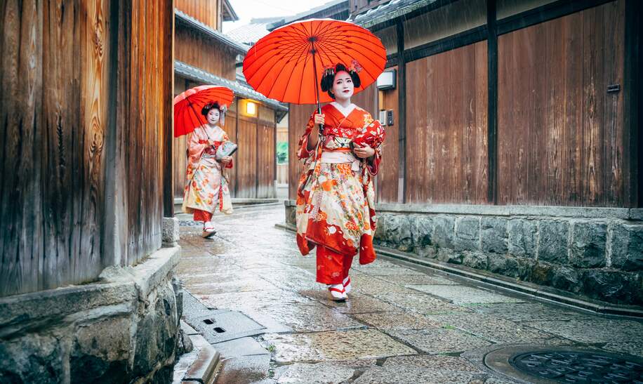 In Kimonos gekleidete Maiko Frauen laufen mit Schirmen durch den Regen  in Kyoto | © Gettyimages.com/FilippoBacci