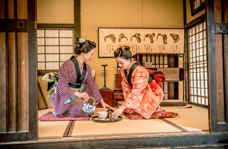 Zwei Frauen in traditionellen Kimonos fuehren eine japanische Teezeremonie in einem klassischen Tatami-Raum durch. | © gettyimages.com/Ababsolutum