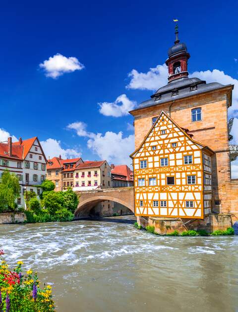 Blick auf das Rathaus und eine mit Blumen geschmückte Brücke in Bamberg | © Gettyimages.com/emicristea