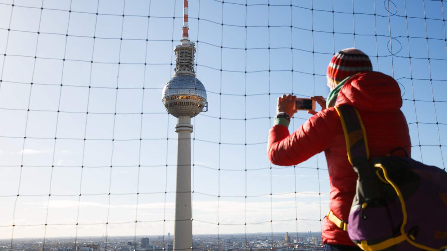 Tourist fotografiert den monumentalen Fernsehturm, der den Himmel über Berlin beherrscht. | © Gettyimages.com/zlikovec