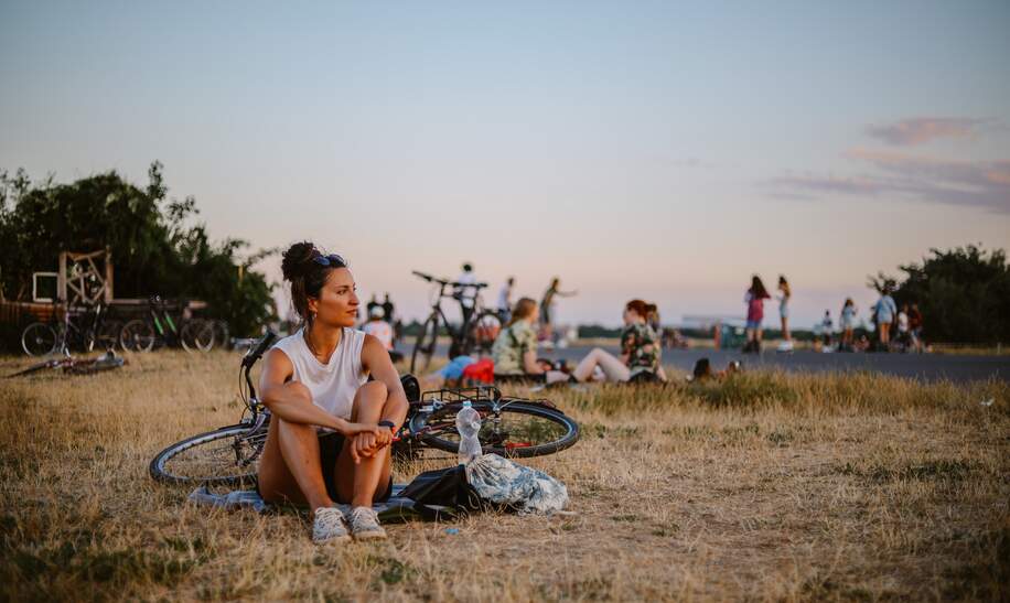 Eine Pendlerin oder eine Touristin, die einen schönen Tag genießt, fährt mit ihrem Fahrrad durch Tempelhof, eine große Freifläche des ehemaligen Flughafens. | © Gettyimages.com/lechatnoir