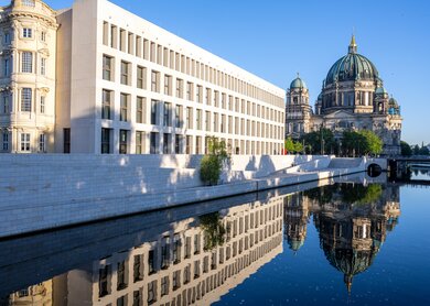 Das wiederaugebaute Berliner Stadtschloss auf dem Humboldt Forum mit dem Dom, der sich in der Spree spiegelt | © Gettyimages.com/elxeneize