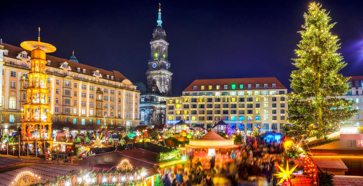 Blick über den Dresdener Weihnachtsmarkt, den Striezelmarkt, mit Weihnachtsbaum und -pyramide, bunt beleuchteten Ständen und der Kreuzkirche im Hintergrund | © Gettyimages.com/Juergen Sack