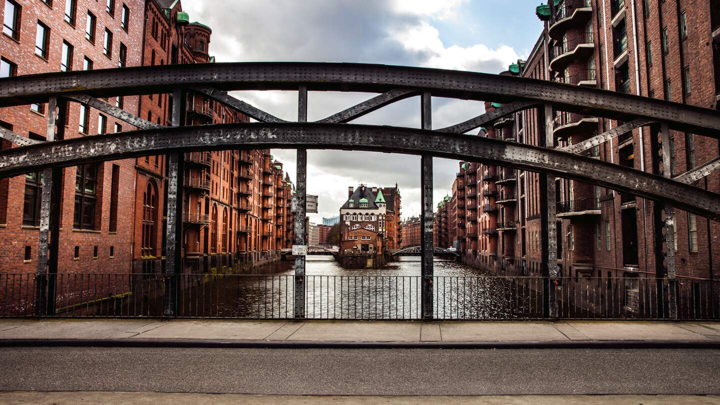 Speicherstadt in Hamburg mit Wasser und Backsteinhäusern hinter einem halbrunden Brückenträger | © Gettyimages.com/Leonardo  Patrizi