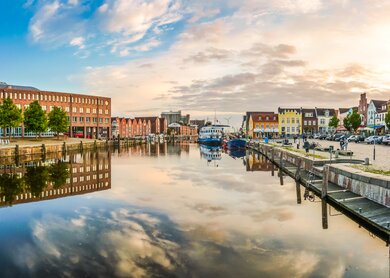 Blick auf den Hafen von Husum, Schleswig-Holstein, in warmen Sonnenlicht mit Spiegelung auf dem Wasser | © © Gettyimages.com/bluejayphoto