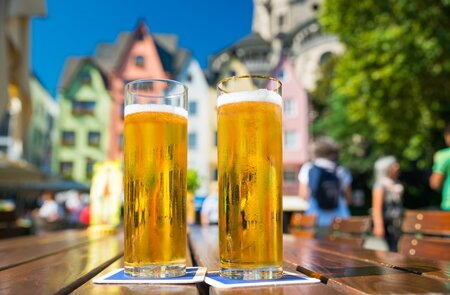 Biergläser auf einem Tisch in Köln, im Hintergrund die bunten Häuser der Kölner Alstadt. | © Gettyimages.com/jotily