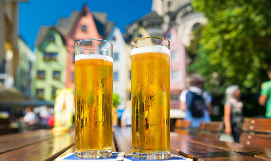 Biergläser auf einem Tisch in Köln, im Hintergrund die bunten Häuser der Kölner Alstadt. | © Gettyimages.com/jotily
