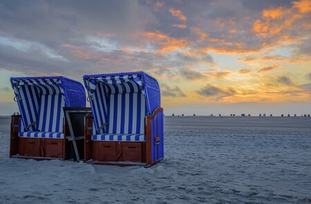 Zwei Strandsessel nebeneinander am weißen Sandstrand mit Sonnenuntergang Dämmerung im Himmel | © Gettyimages.com/frederickdoerschem