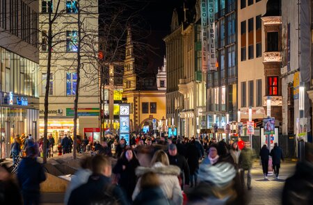 Nachtansicht der Fußgängerzone mit überfüllten Straßen von Menschen, die einkaufen in Leipzig  | © Gettyimages.com/holgs