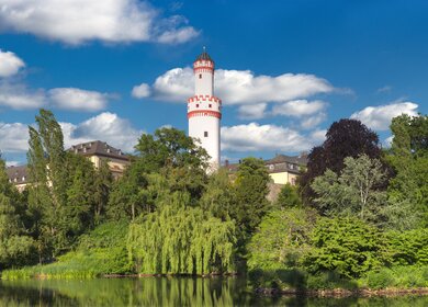 Panoramafoto des weissen Turms des Bad Homburger Schlosses vom oeffentlich zugaenglichen Schlosspark bei sonnigem Wetter mit leichter Bewoelkung | © Gettyimages.com/Frank Wagner