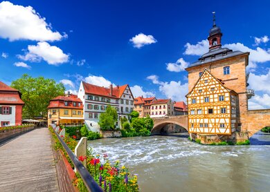 Blick auf das Rathaus und eine mit Blumen geschmueckte Bruecke in Bamberg | © Gettyimages.com/emicristea