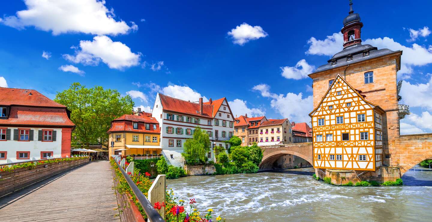 Blick auf das Rathaus und eine mit Blumen geschmueckte Bruecke in Bamberg | © Gettyimages.com/emicristea