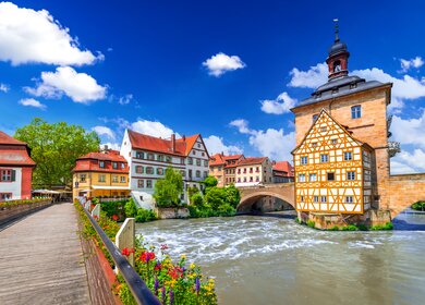 Blick auf das Rathaus und eine mit Blumen geschmückte Brücke in Bamberg | © Gettyimages.com/emicristea