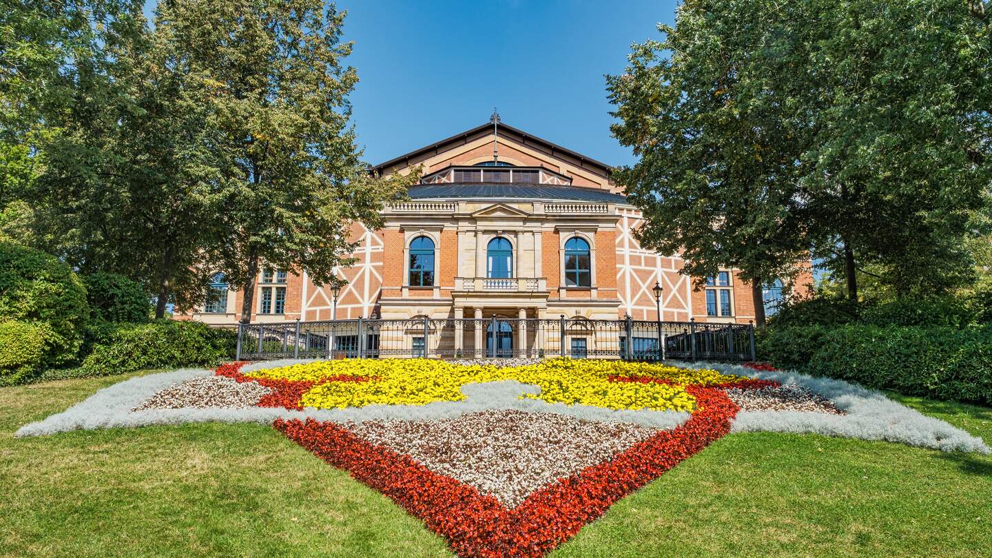 Die Front des Festspiehauses mit einem geometrisch und davor ein farblich gestalteten Blumenbeet in Bayreuth, Deutschland | © GettyImages.com/Harald007