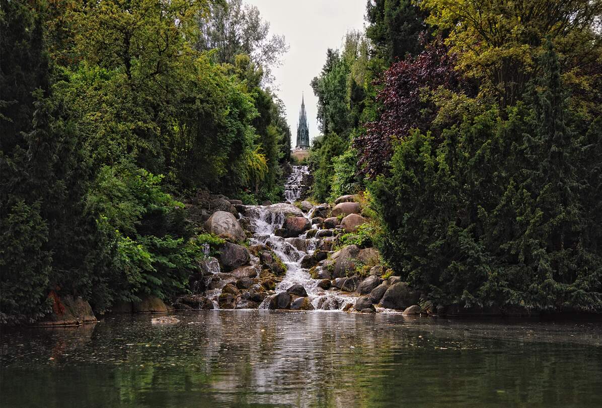 Menschen ruhen sich aus und beobachten den Wasserfall am Nationaldenkmal auf dem Kreuzberg im Viktoriapark, Berlin.  | © Gettyimages.com/hsvrs