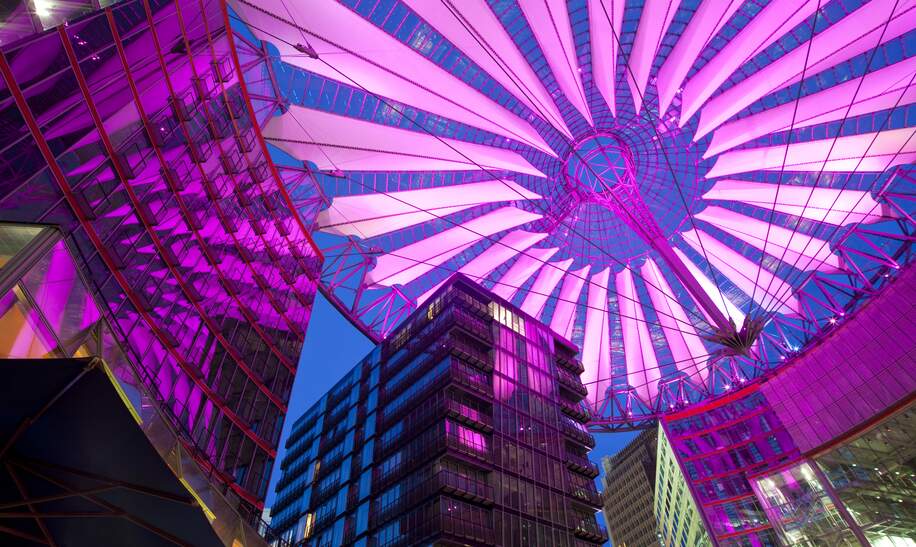 Das Sony Center am Potsdamer Platz mit violett beleuchtetem Lamellen-Zeltdacham am Abend | © Gettyimages.com/Ingenui