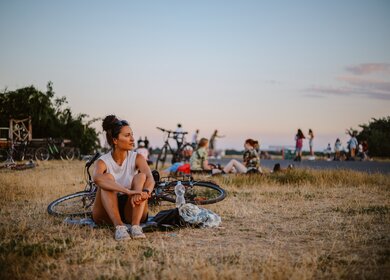 Eine Pendlerin oder eine Touristin, die einen schönen Tag genießt, fährt mit ihrem Fahrrad durch Tempelhof, eine große Freifläche des ehemaligen Flughafens. | © Gettyimages.com/lechatnoir