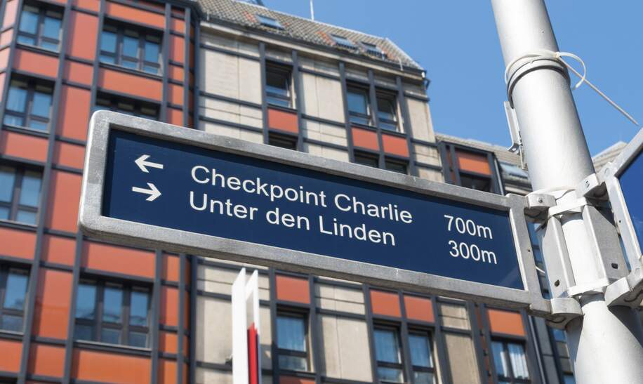 Straßenschild in der berühmten Friedrichstraße in Berlin mit Checkpoint Charlie und weiteren bekannten Sehenswürdigkeiten | © Gettyimages.com/hansenn
