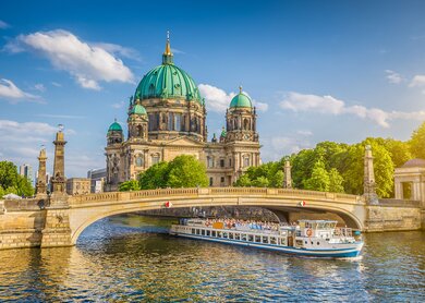 Berliner Dom an der Spree mit Schiff, dass unter der einer Brücke fährt | © Gettyimages.com/JR Photography