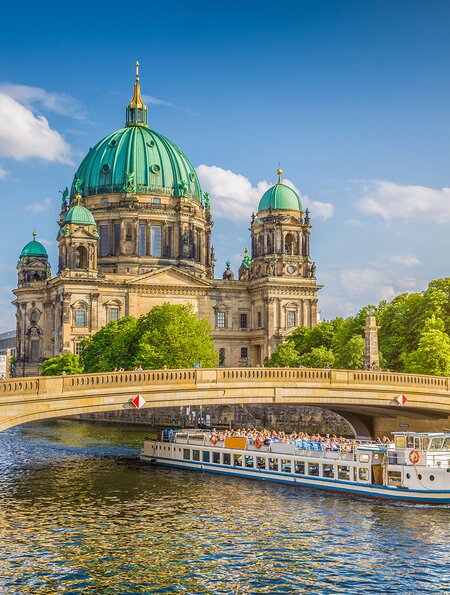 Berliner Dom an der Spree mit Schiff, dass unter der einer Brücke fährt | © Gettyimages.com/JR Photography