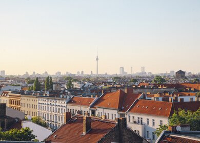 Blick auf das Berliner Panorama vom Dach Neukoellns. Alte Gebaeude sowie das Stadtzentrum mit dem beruehmten Wahrzeichen des Fernsehturms sind unter dem hellen und klaren Himmel zu sehen. | © Gettyimages.com/lechatnoir
