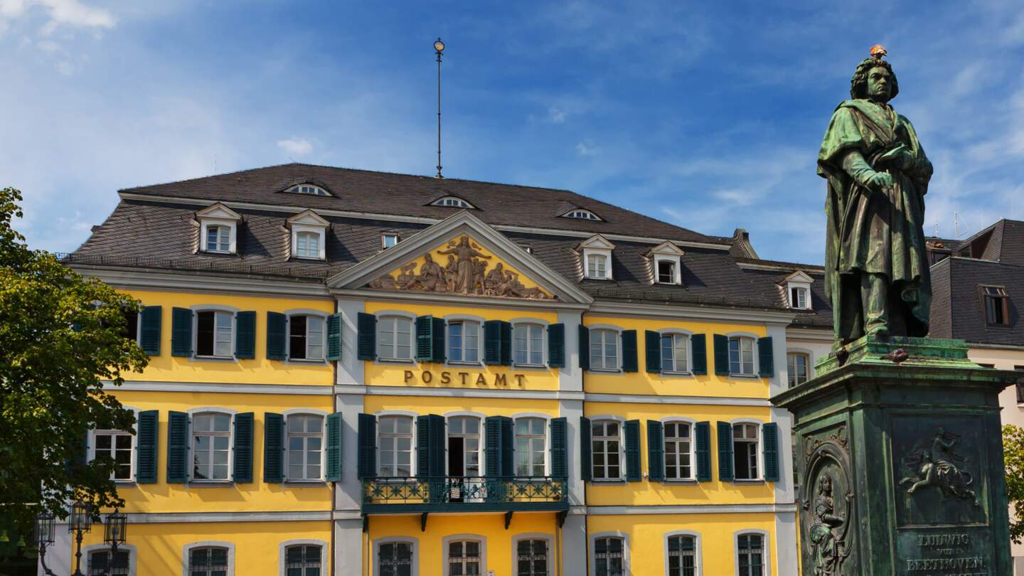 Blick auf Beethoven-Denkmal und Postamt auf dem Münsterplatz in Bonn bei blauem Himmel | © GettyImages.com/burcintuncer