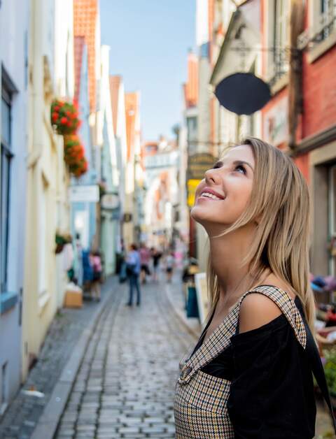 Eine junge Frau spaziert auf einer mittelalterlichen Straße in Bremen | © Gettyimages.com/Massonstock