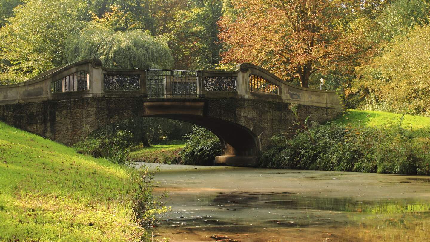 Schoene Bruecke ueber einen kleinen Kanal im herblichen Buergerpark im Stadtzentrum von Bremen | © GettyImages.com/Darkroomluster