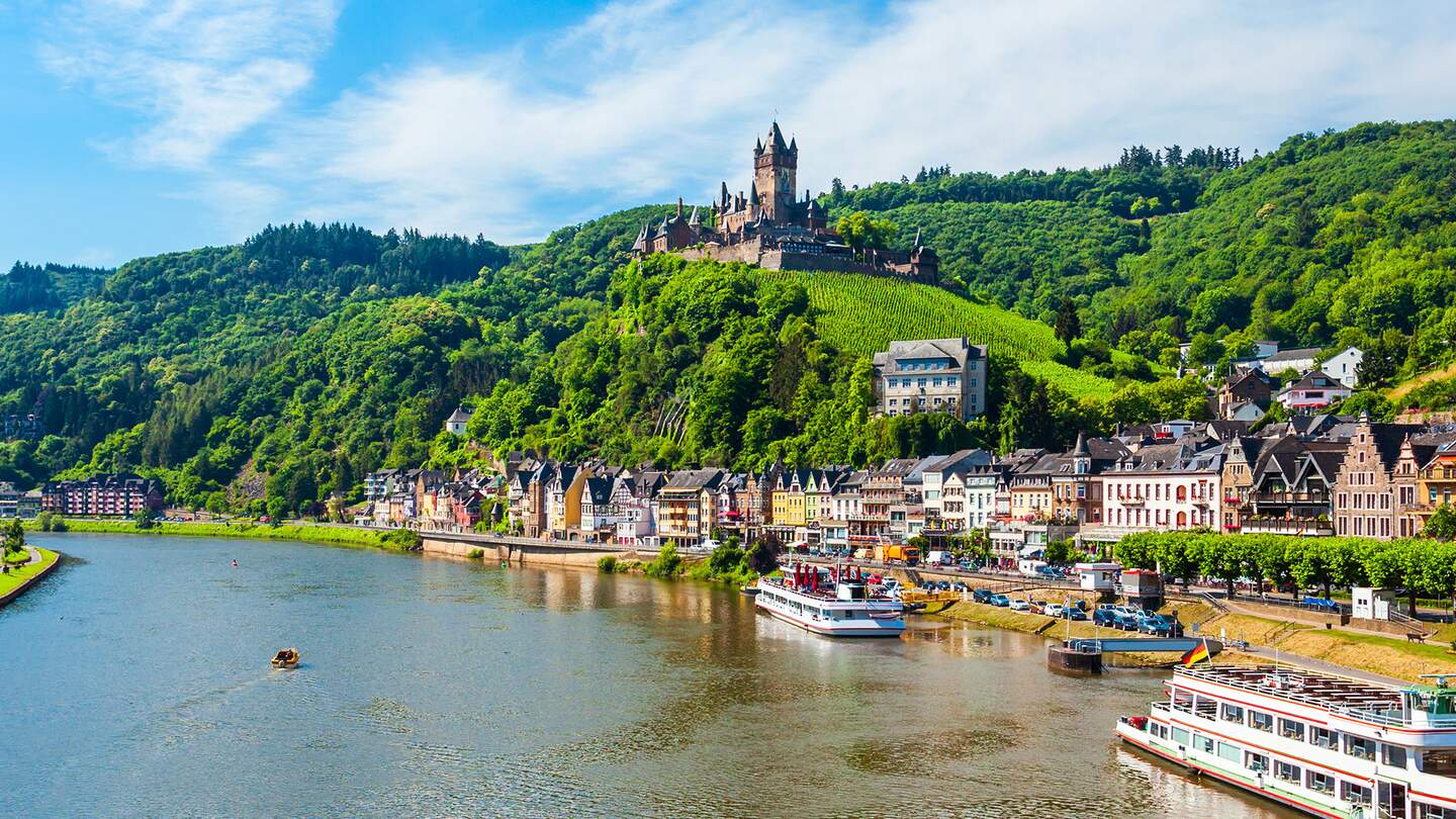 Wunderschoener Stadtblick auf die historische Altstadt von Cochem mit den typischen fachwerkbunten Haeusern, Hotels und Restaurants, Wahrzeichen der Reichsburg auf einem Berg, Mosel im sonnigen Fruehling  | © GettyImages.com/saiko3p