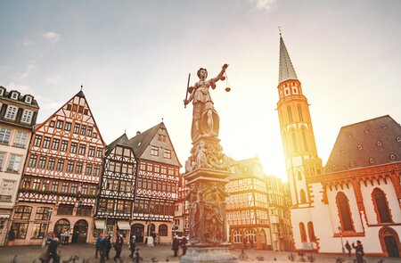 Frankfurts Fachwerkhaeuser am Roemer mit dem Gerechtigkeitsbrunnen im Vordergrund bei Sonnenuntergang | © Gettyimages.com/serts