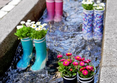 Gummistiefel im Wasser mit Blumen in der Stadt Freiburg | © Gettyimages.com/m_pavlov