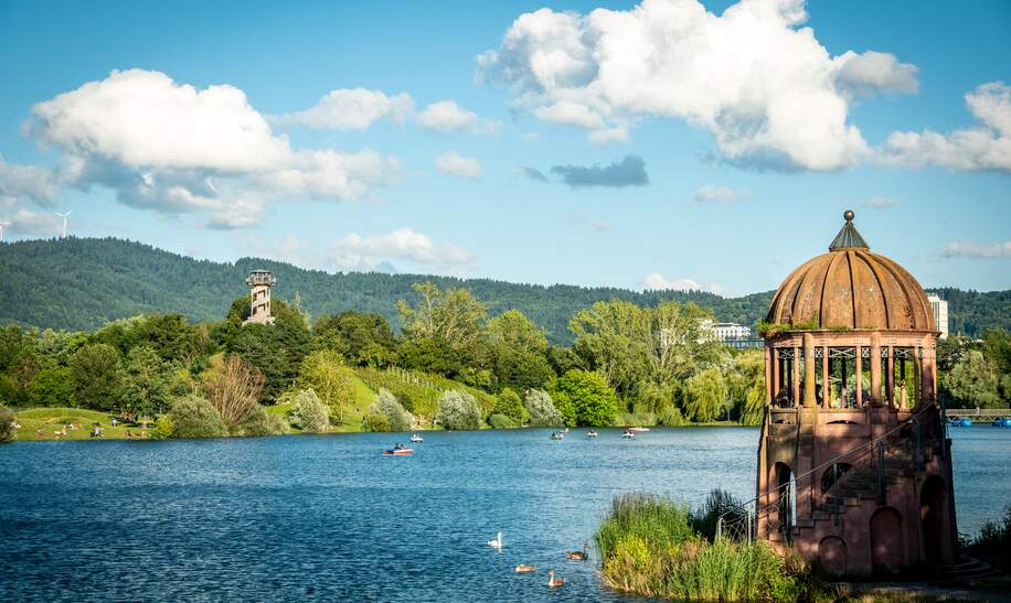 Buntes Panorama des Flueckiger Sees mit zwei Aussichtstuermen am Seepark in Freiburg | © GettyImages.com/Andreas Naegeli