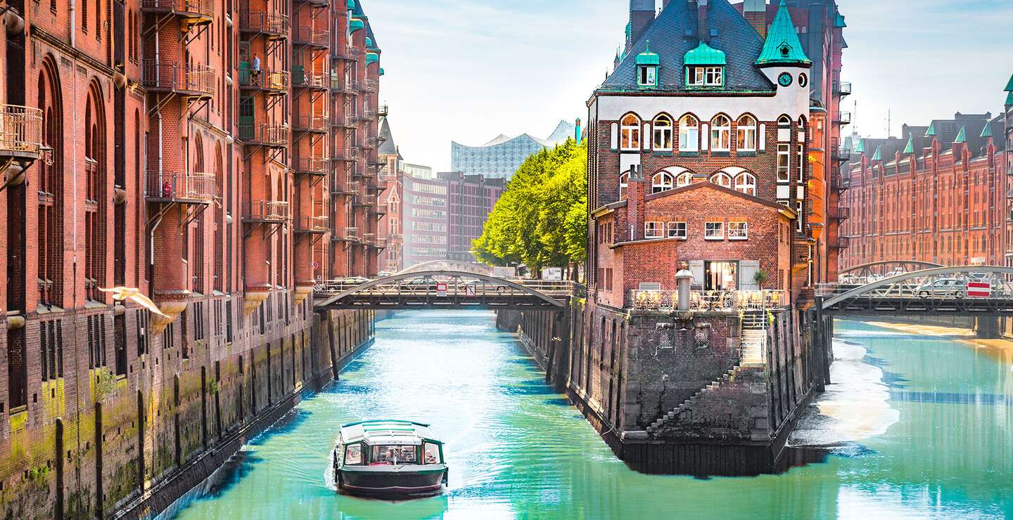 Speicherstadt in Hamburg mit einem Tourboot auf dem Wasser | © Gettyimages.com/bluejayphoto