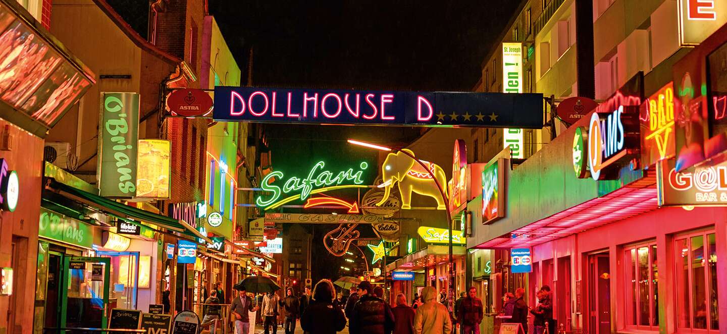 Reeperbahn Hamburg bei Nacht mit leuchtenden Schildern. Im Vordergrund ist Dollhouse zu lesen. | © Gettyimages.com/Juergen Sack