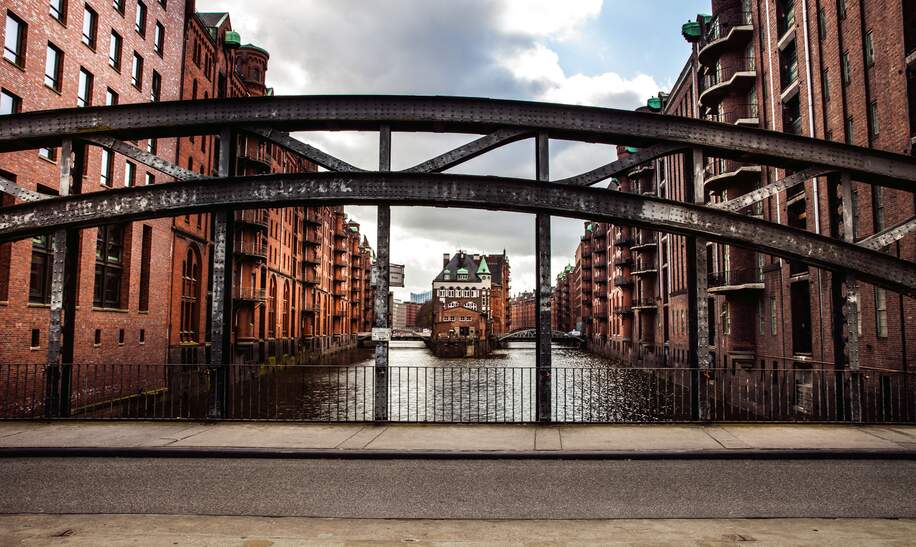 Speicherstadt in Hamburg mit Wasser und Backsteinhaeusern hinter einem halbrunden Brueckentraeger | © Gettyimages.com/Leonardo  Patrizi