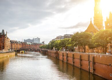 Wunderschoener Stadtblick auf den Wasserkanal mit alter Kirche in Hamburg-Stadt waehrend des Sonnenuntergangs | © gettyimages.com/RossHelen