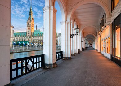 Hamburger Innenstadt, Alsterarkaden mit Rathaus bei Sonnenuntergang. | © Gettyimages.com/RudyBalasko