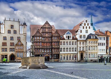 Der Marktplatz in Hildesheim mit seinen zahlreichen historischen Fachwerkhäusern im Vorgrund ein historischer Brunnen | © GettyImagse.com/Borisb17