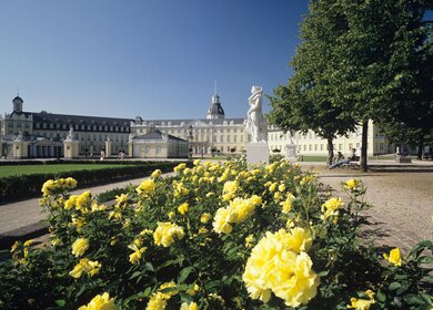 Schloss Karlsruhe mit gelben Rosen im Vordergrund und blauem Himmel | © Gettyimages.com/rotofrank